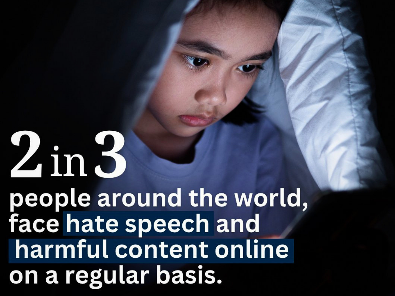 Young child under blanket using smartphone at night, illustrating online safety statistic that 2 in 3 people globally face hate speech and harmful content online regularly